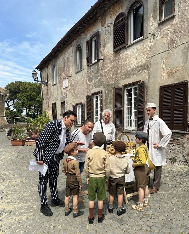 il regista igor righetti spiega una scena ai bambini con lui il produttore massimiliano filippini e il direttore della fotografia gianni mammolotti